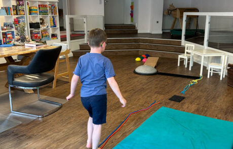 Therapie im Therapieraum: Kind läuft über ein Seil